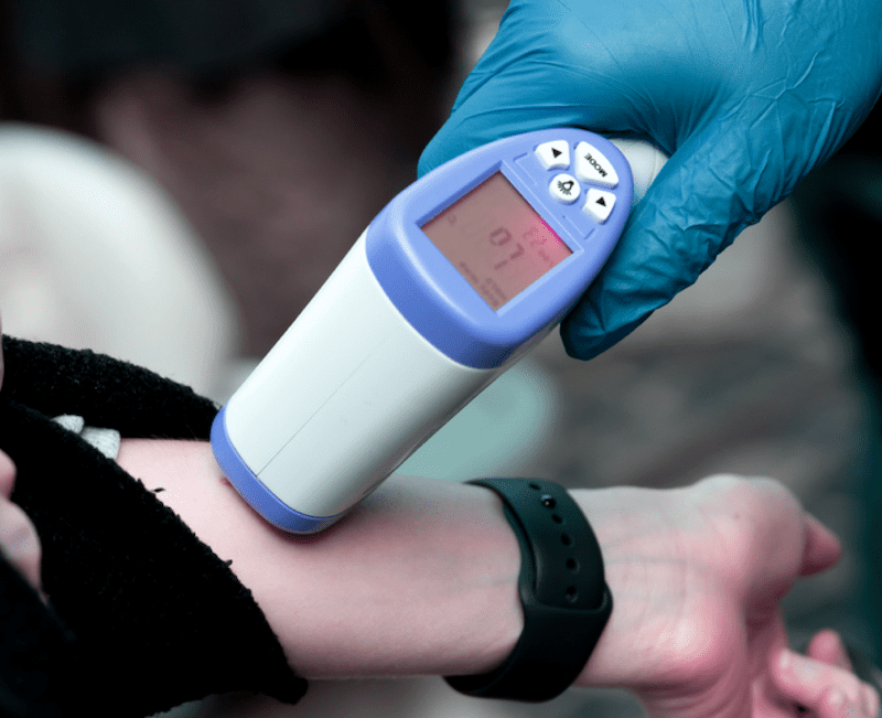 temperature checks on an employees arm indicating contactless employee screening